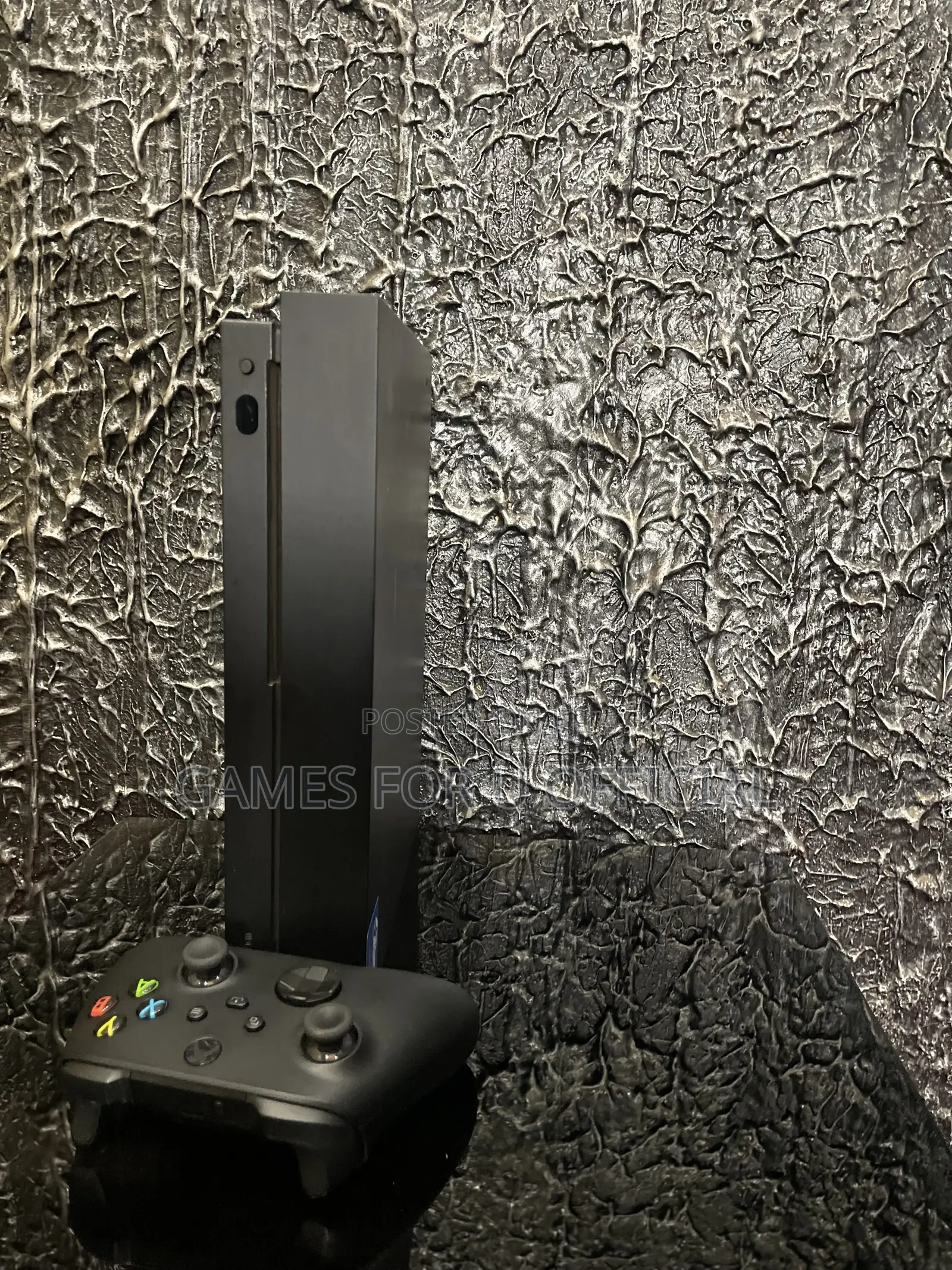 Xbox One X With a Black Controller and a Game