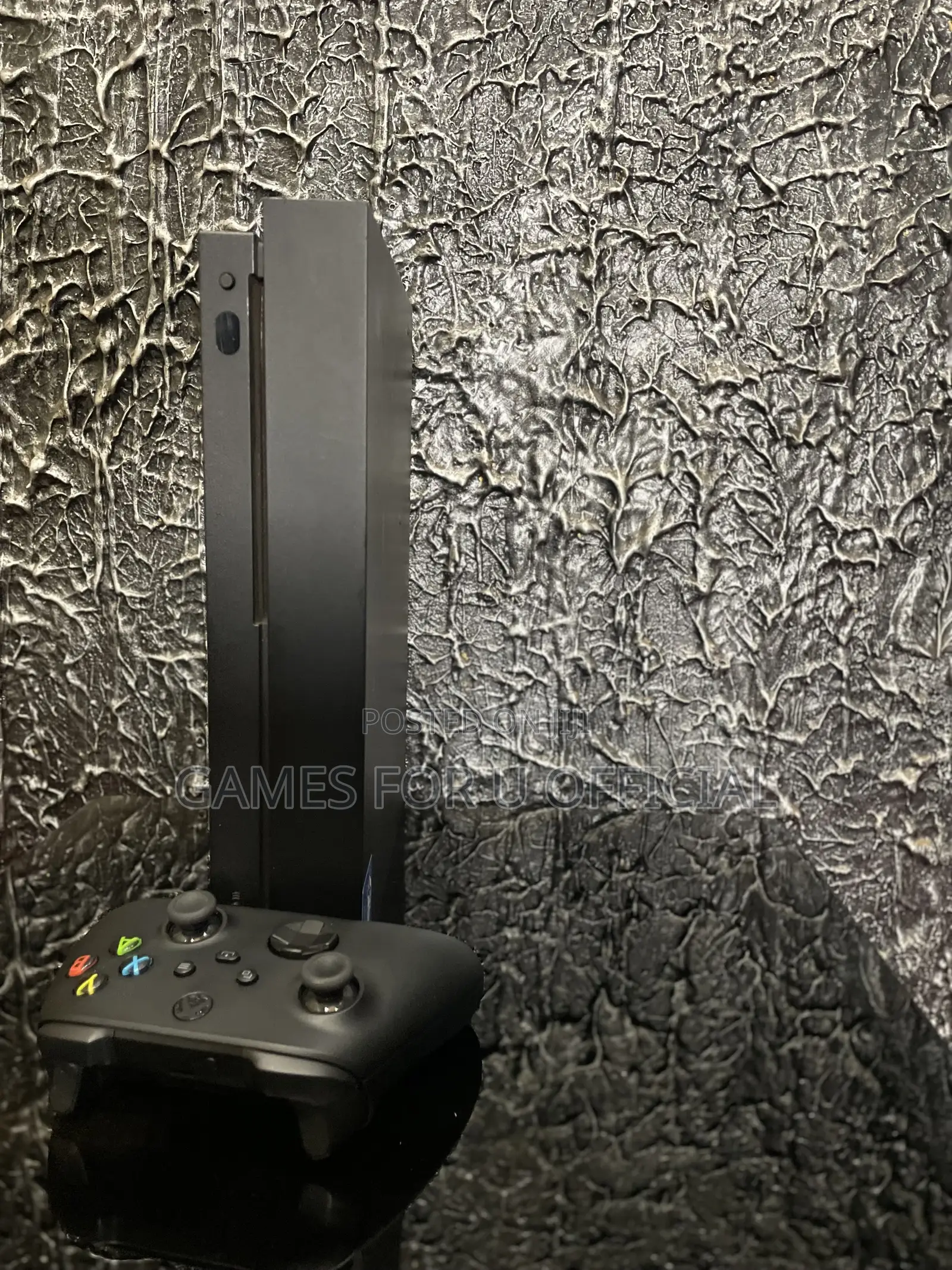 Xbox One X With a Black Controller and a Game