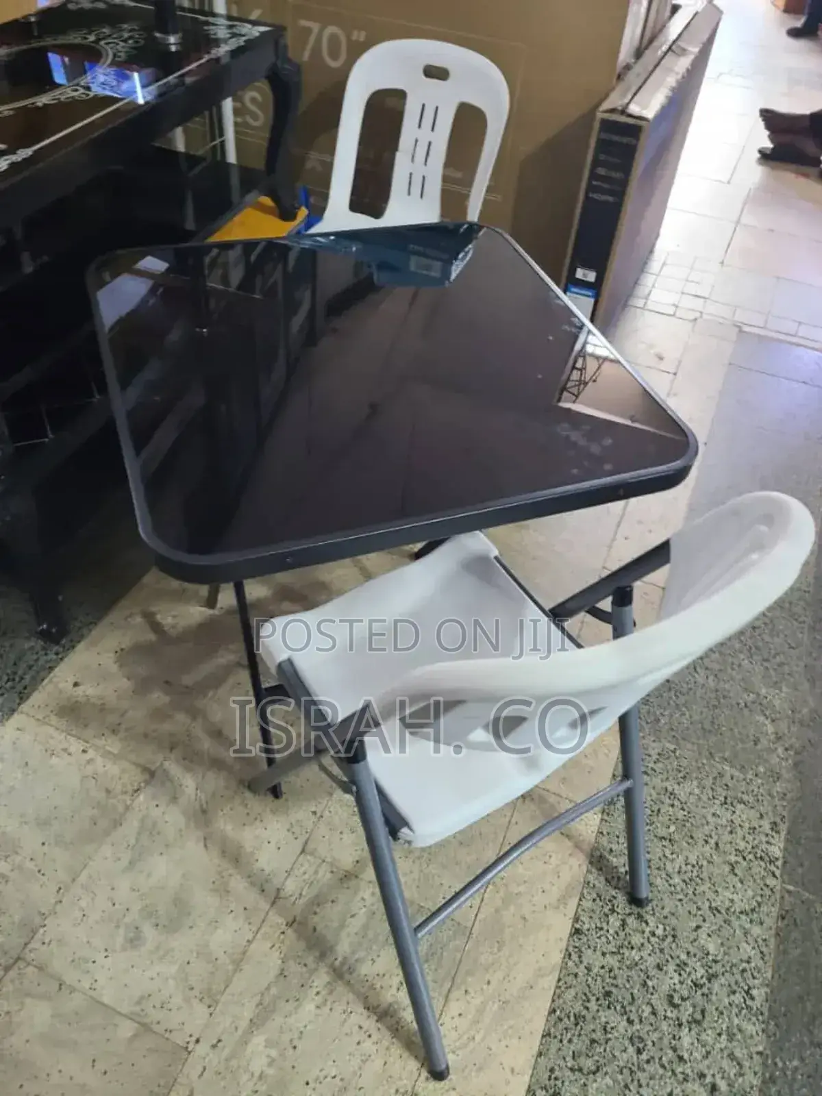 A Foldable Glass Dining Table With Two Folding Chairs.