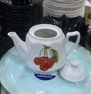 A Round Ceramic White Tea Pot With a Flower