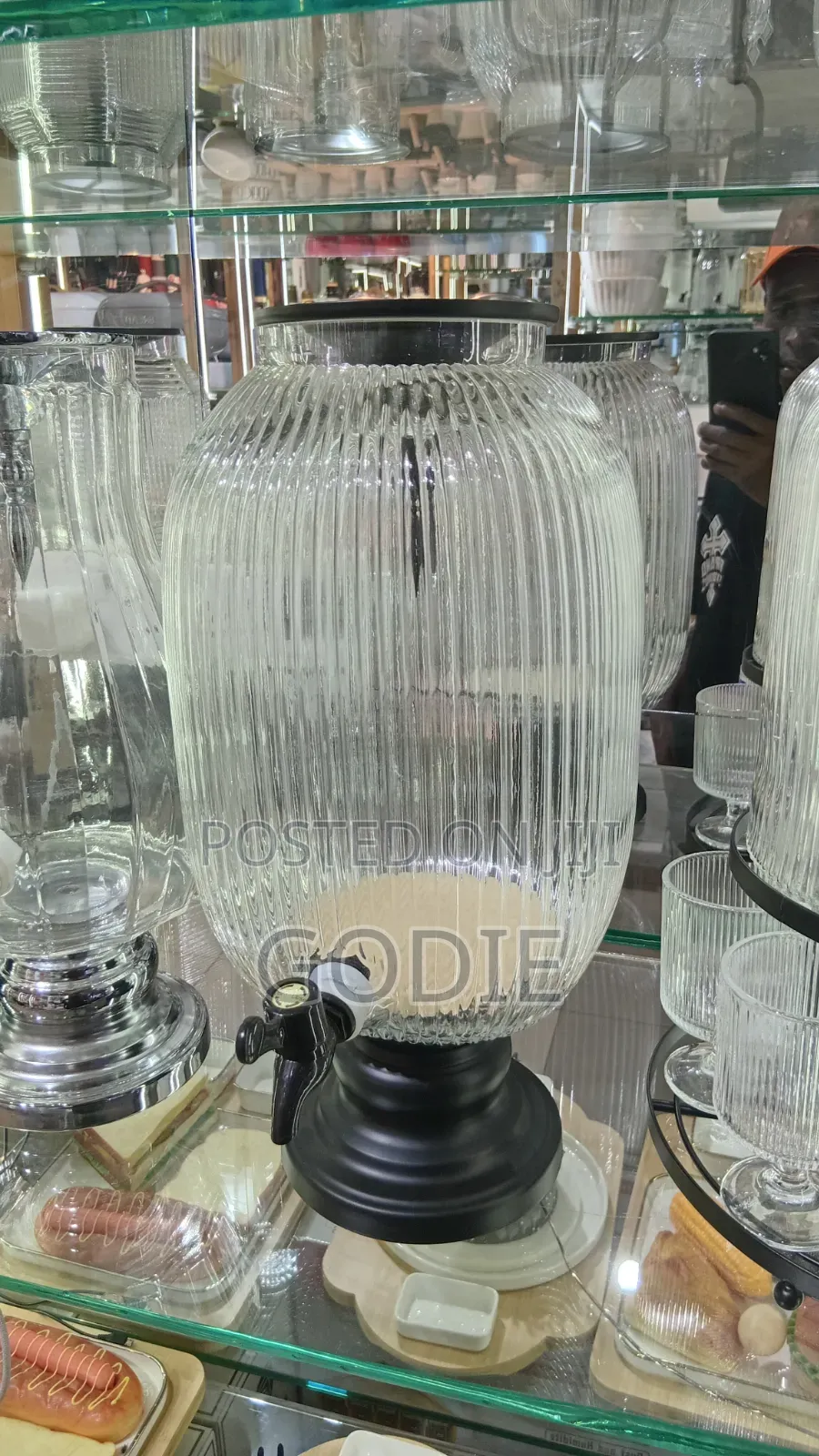 Ribbed Glass Beverage Dispenser With a Black Tap and Stand.