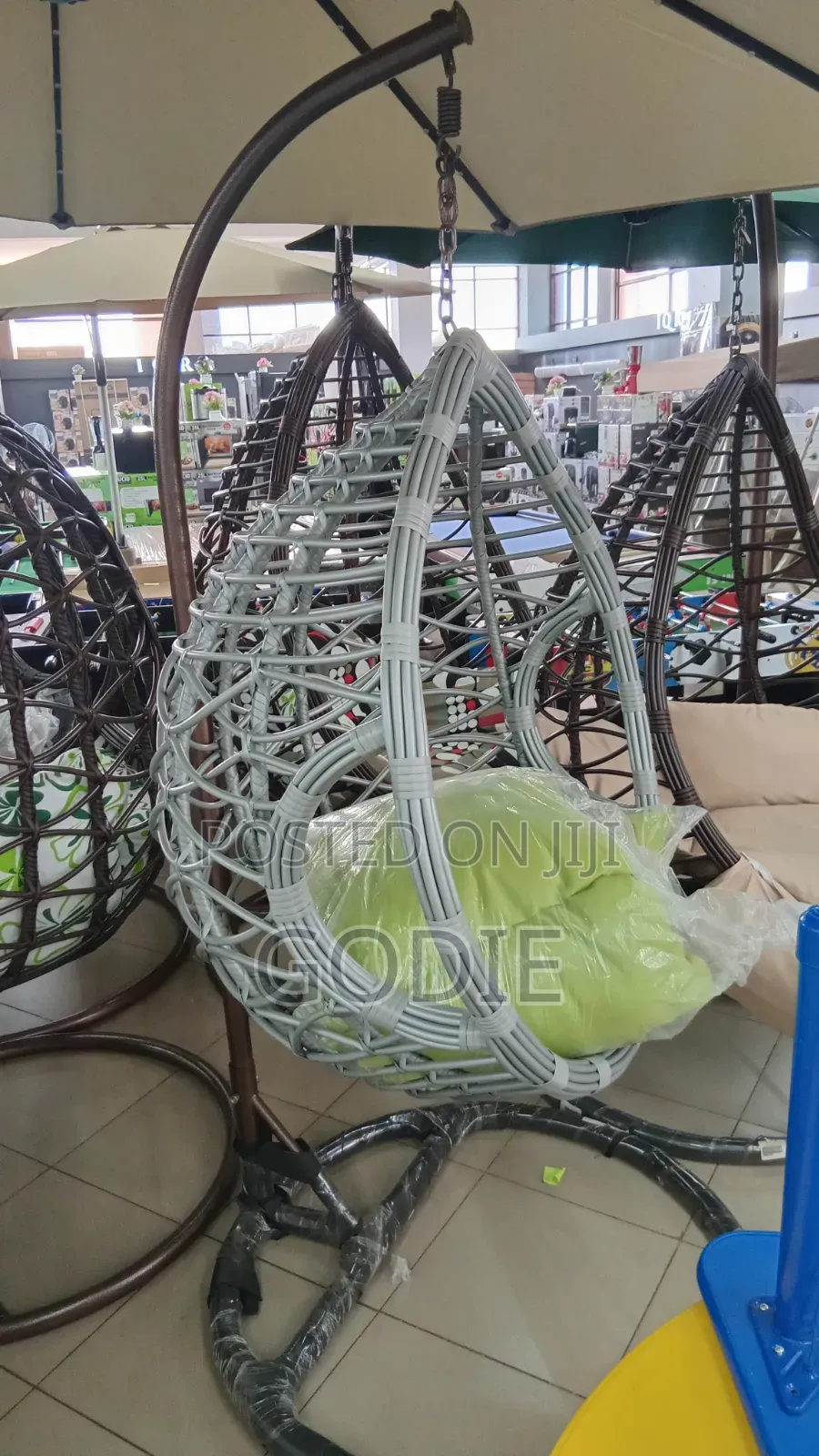 Egg-Shaped Swing With a Metal Stand and a Lime Green Cushion.