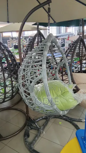 Egg-Shaped Swing With a Metal Stand and a Lime Green Cushion.
