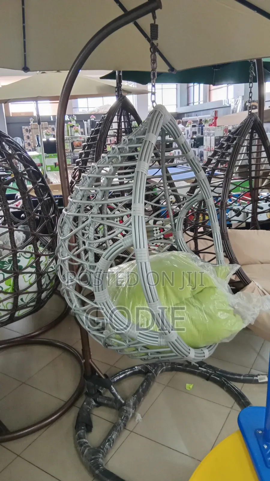 Egg-Shaped Swing With a Metal Stand and a Lime Green Cushion.